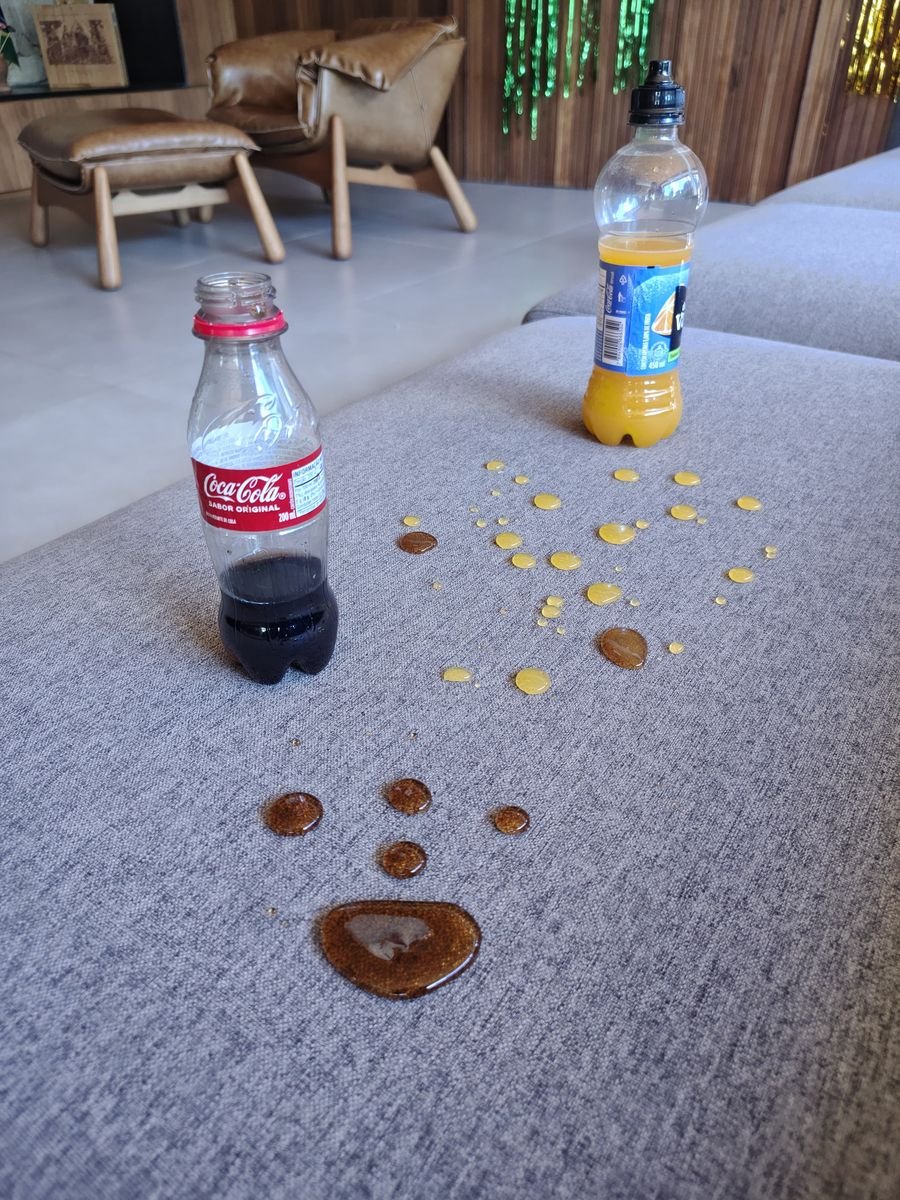 Refrigerante e suco em gotas sobre sofá cinza impermeabilizado pela Inove